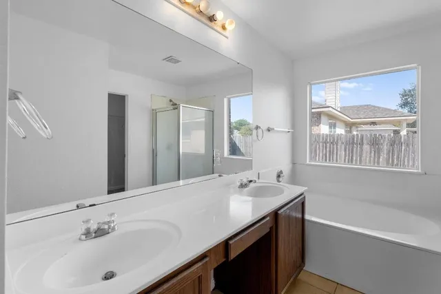 a bathroom with a tub a sink and mirror