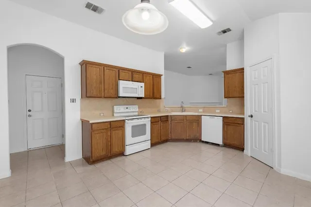 a large white kitchen with a sink dishwasher a stove and a refrigerator with wooden floor