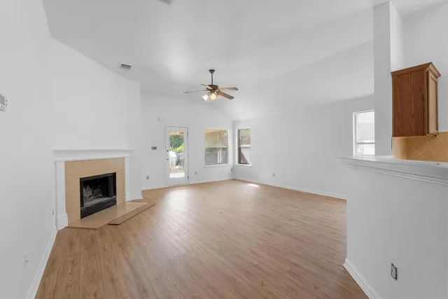 an empty room with wooden floor fireplace and windows