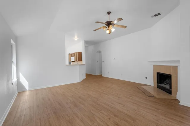 a view of an empty room with wooden floor and a fireplace