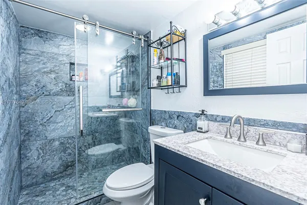 a bathroom with a granite countertop sink toilet and shower