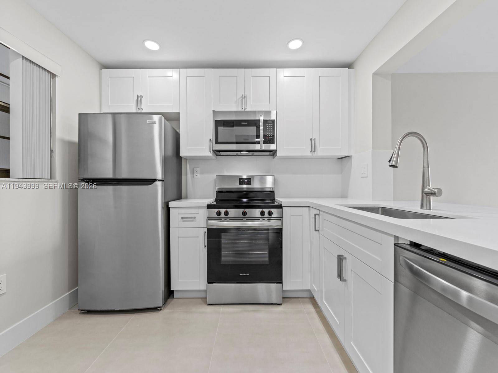 a kitchen with stainless steel appliances a refrigerator stove and white cabinets