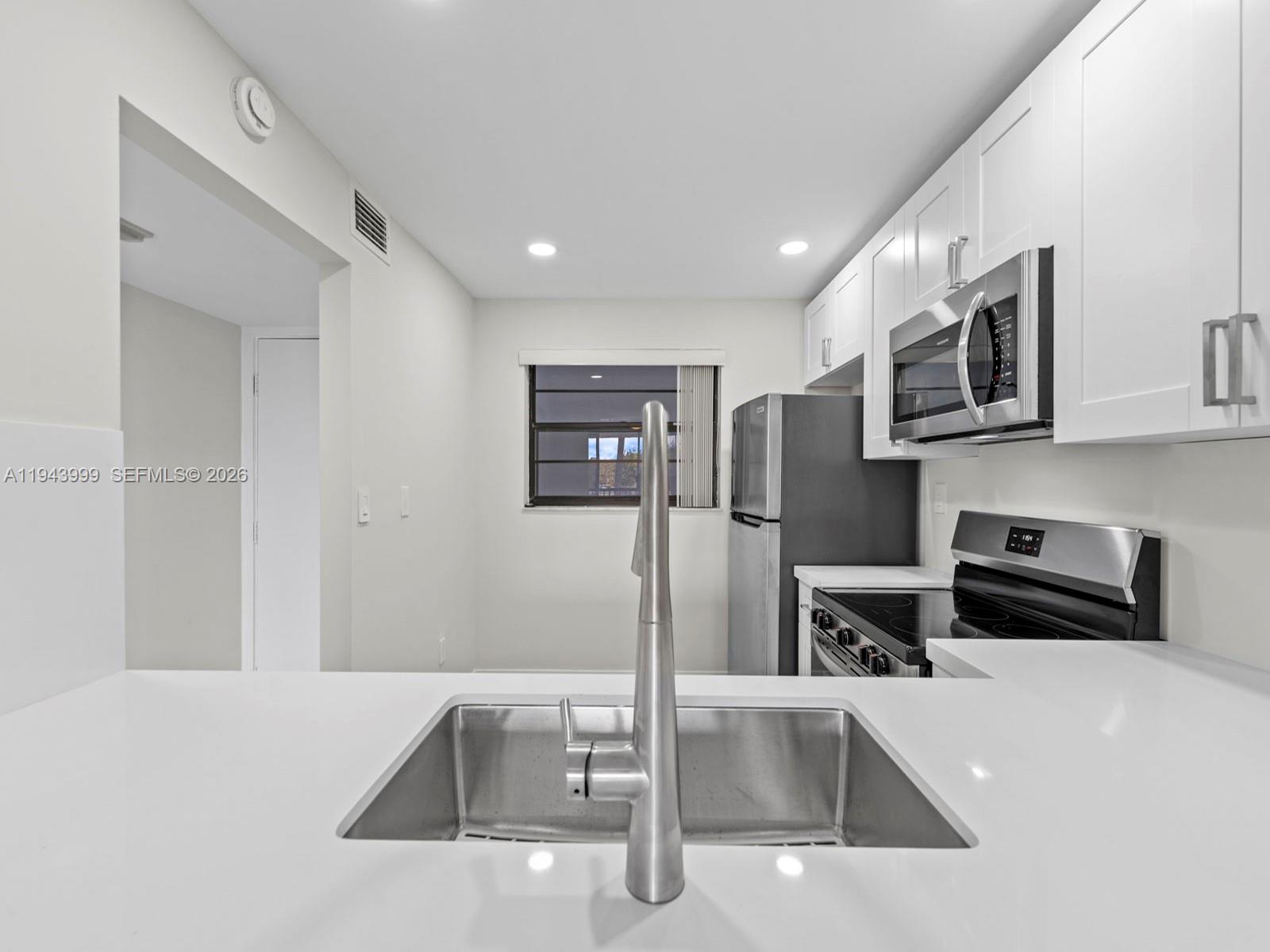 10825 Southwest 112th Avenue, Unit 206 Miami, FL 33176 - Photo 4 of 32 a kitchen with stainless steel appliances a microwave a sink and a refrigerator