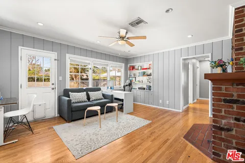 a living room with furniture a large window and wooden floor