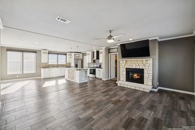 a view of a livingroom with a fireplace a ceiling fan and windows
