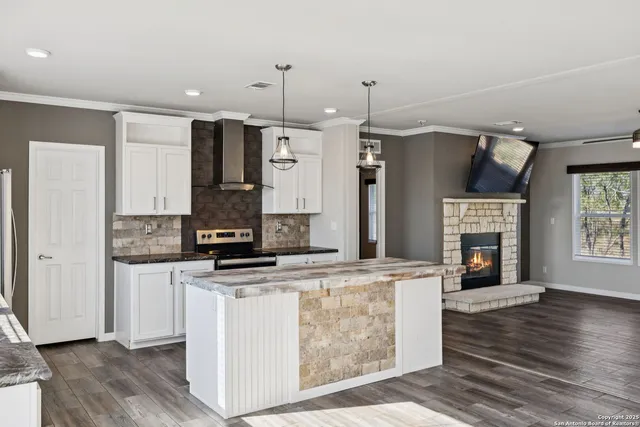 a kitchen with stainless steel appliances granite countertop a stove a refrigerator a oven and white cabinets with wooden floor