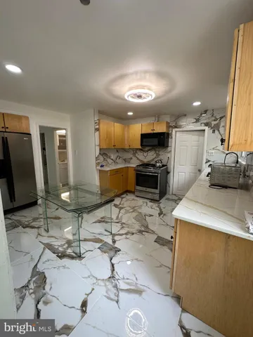 a open kitchen with kitchen island granite countertop a sink cabinets and stainless steel appliances