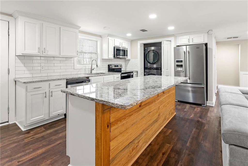 a large kitchen with stainless steel appliances granite countertop a refrigerator and a stove top oven