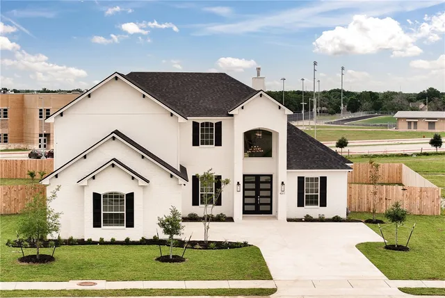 a view of a white house with a yard and potted plants