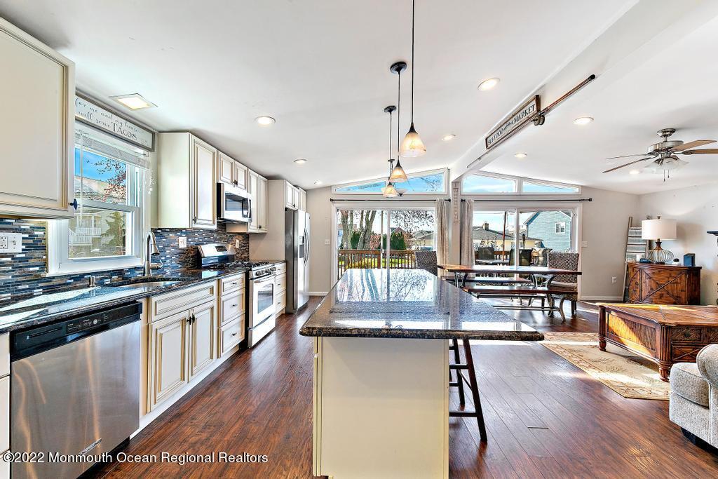36 Cabana Drive Brick, NJ 08723 - Photo 14 of 42 a kitchen with stainless steel appliances granite countertop a stove top oven a sink a dining table and chairs with wooden floor