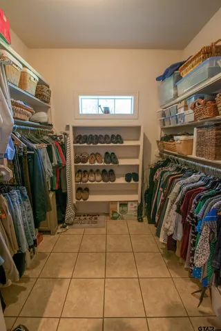 a view of walk in closet with clothes and shoes