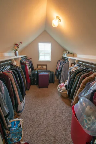 a view of walk in closet with clothes and shoes