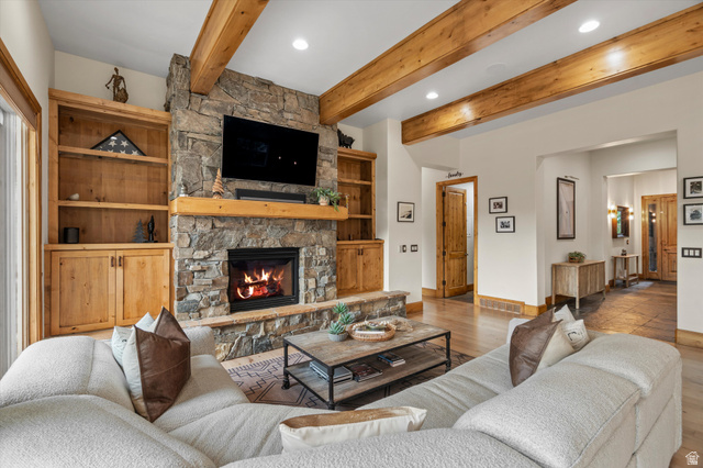4892 Eagle Rdg Drive Eden, UT 84310 - Photo 2 of 39 Living area featuring a stone fireplace with a wood mantle, built-in wood shelving, exposed wood ceiling beams, wood-finish flooring, and recessed lighting