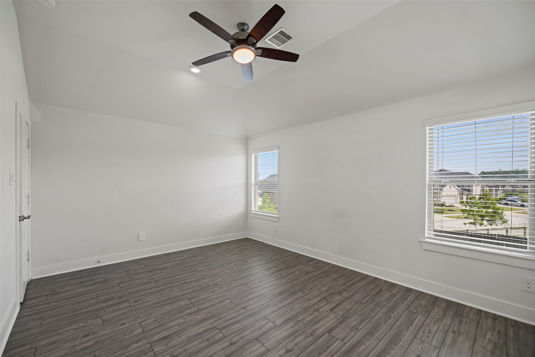 10603 Whitejacket Conroe, TX 77385 - Photo 16 of 42 Bright and spacious Primary Bedroom with sleek wood-look flooring, large windows offering plenty of natural light, and a modern ceiling fan.