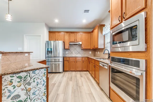 a kitchen with stainless steel appliances granite countertop a sink a stove and a wooden floors