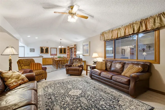 a living room with furniture kitchen view and a chandelier