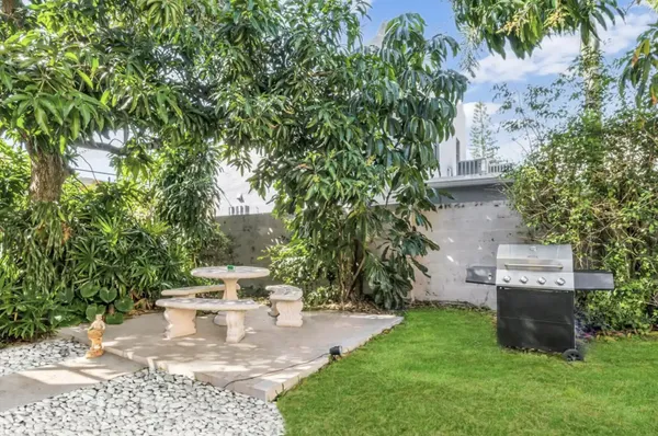 a view of a backyard with potted plants and large trees