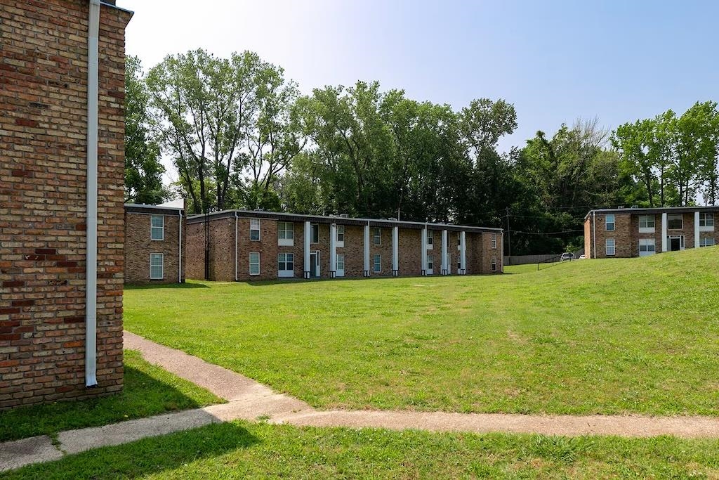 3236 Millington Road Memphis, TN 38127 - Photo 25 of 31 Manicured grassy areas surround multiple brick apartment buildings featuring white structural columns and white window frames