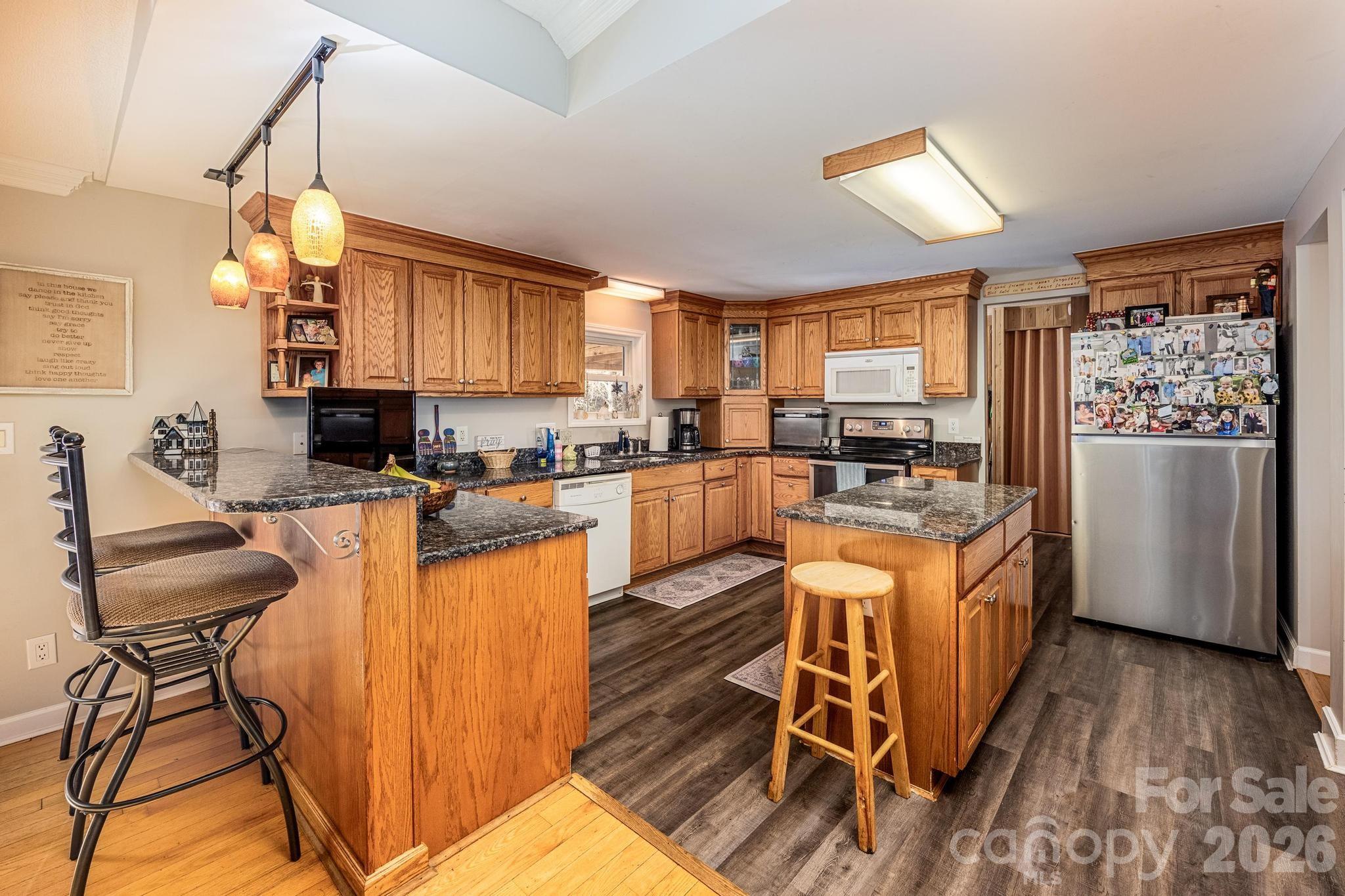 11443 Mooresville Road Davidson, NC 28036 - Photo 33 of 47 a kitchen with stainless steel appliances granite countertop a refrigerator a stove a sink dishwasher a dining table and chairs with wooden floor
