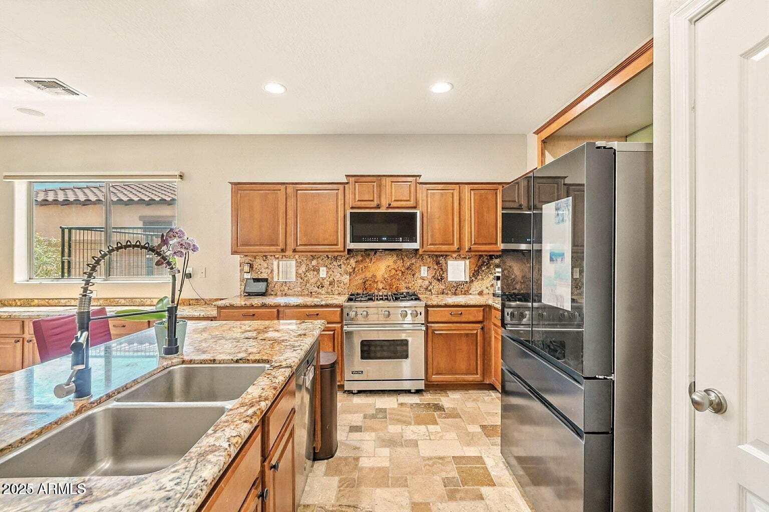 7169 South Dodane Court Gilbert, AZ 85298 - Photo 8 of 23 a kitchen with stainless steel appliances granite countertop a sink stove and refrigerator