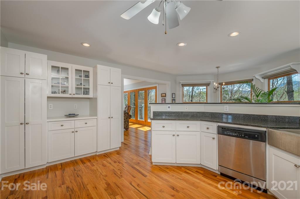 658 South Cove Road Mill Spring, NC 28756 - Photo 17 of 46 a kitchen with granite countertop a stove a sink and white cabinets with wooden floor