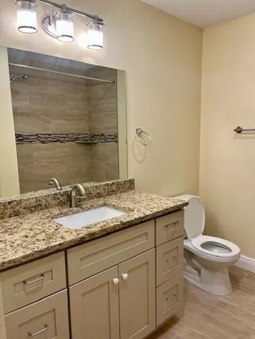 a bathroom with a granite countertop sink a toilet and a mirror