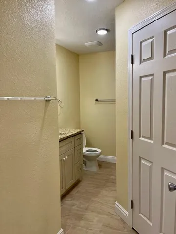 a bathroom with a granite countertop toilet a sink and a mirror