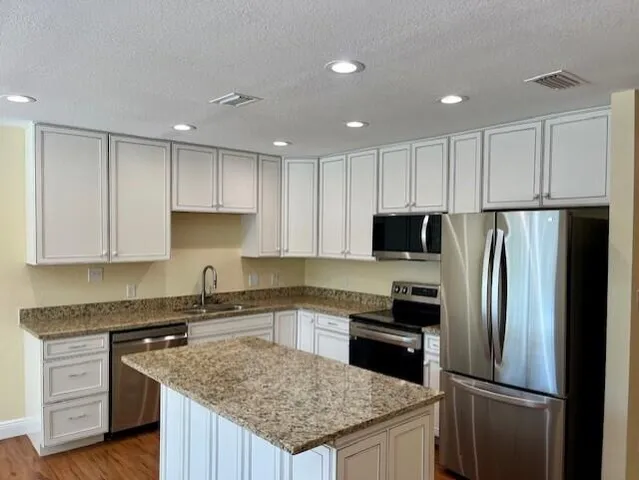 a kitchen with kitchen island granite countertop stainless steel appliances and refrigerator