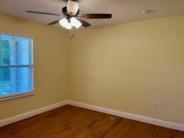 a view of a room with wooden floor a ceiling fan and a window