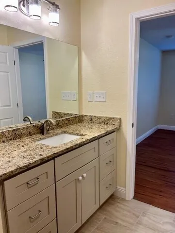 a bathroom with a granite countertop sink and a mirror