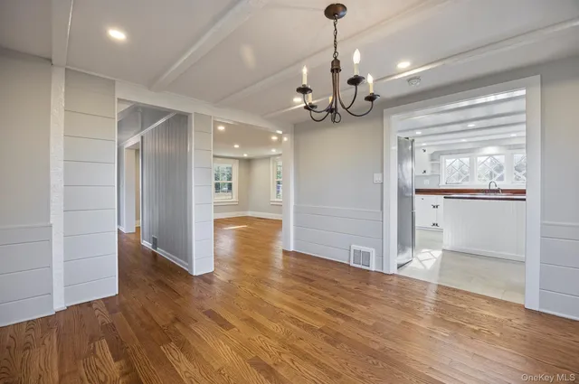 a view of an empty room with wooden floor and a ceiling fan