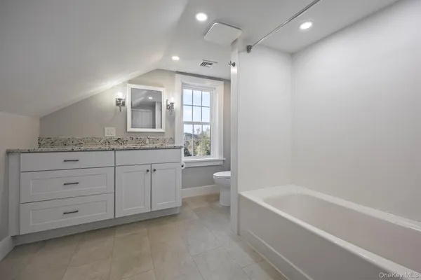 a spacious bathroom with a granite countertop sink a toilet and bathtub