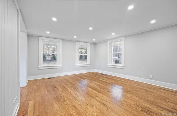 a view of an empty room with wooden floor and window