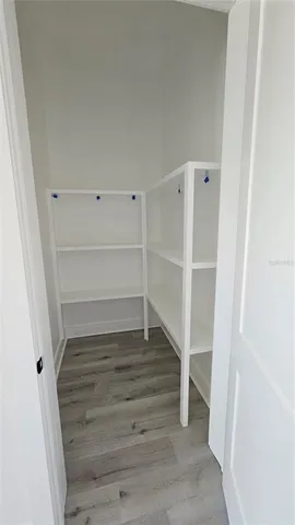 an empty room with wooden floor and a hallway