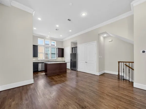 a living room with stainless steel appliances kitchen island hardwood floor and a sink