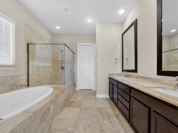 a spacious bathroom with a granite countertop tub sink shower and mirror