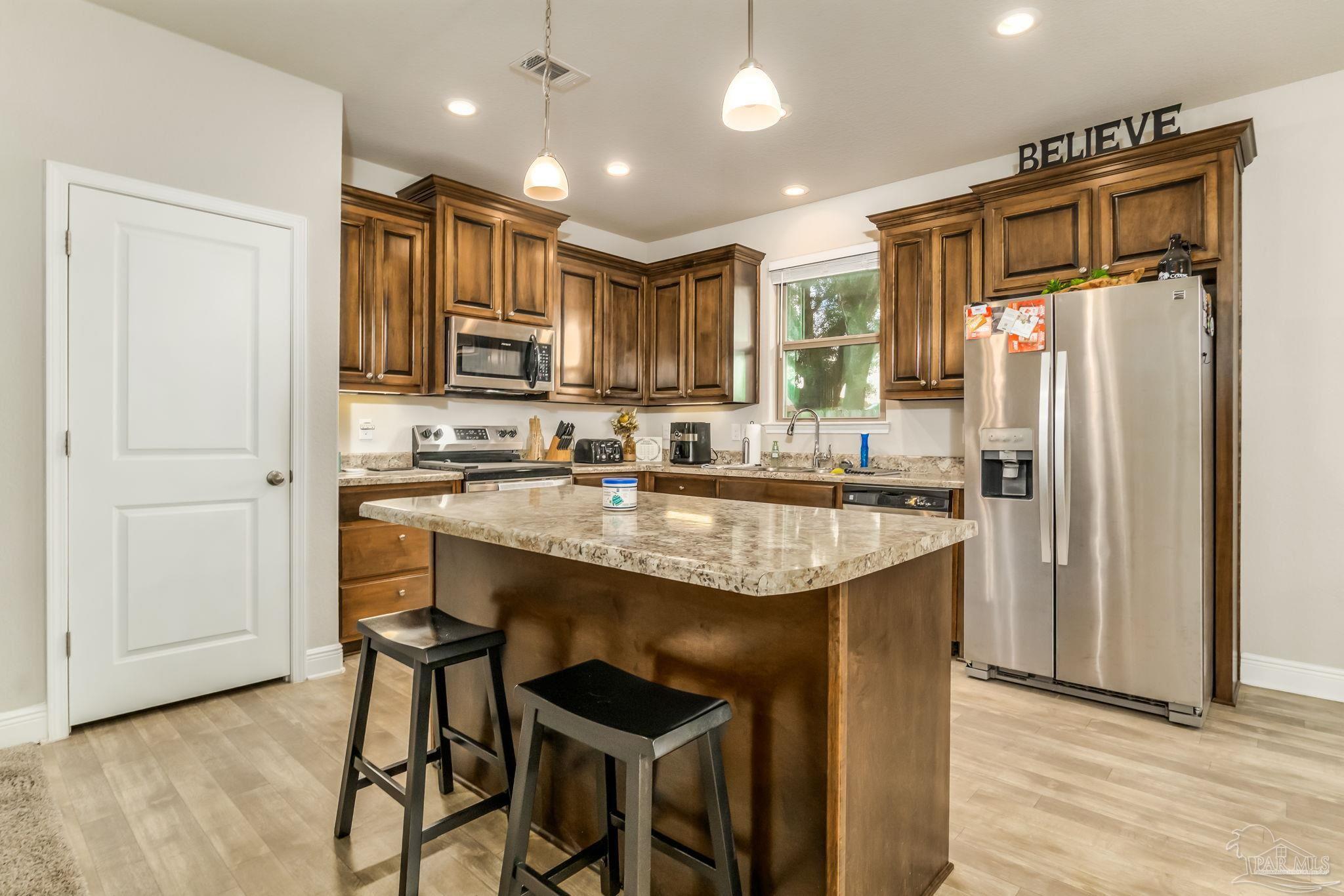 5185 Parkside Drive Pace, FL 32571 - Photo 26 of 43 a kitchen with kitchen island granite countertop wooden cabinets and refrigerator