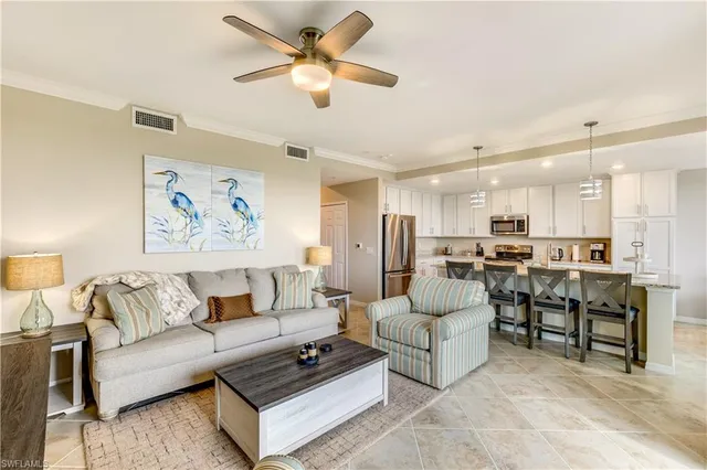 a living room with furniture kitchen view and a chandelier
