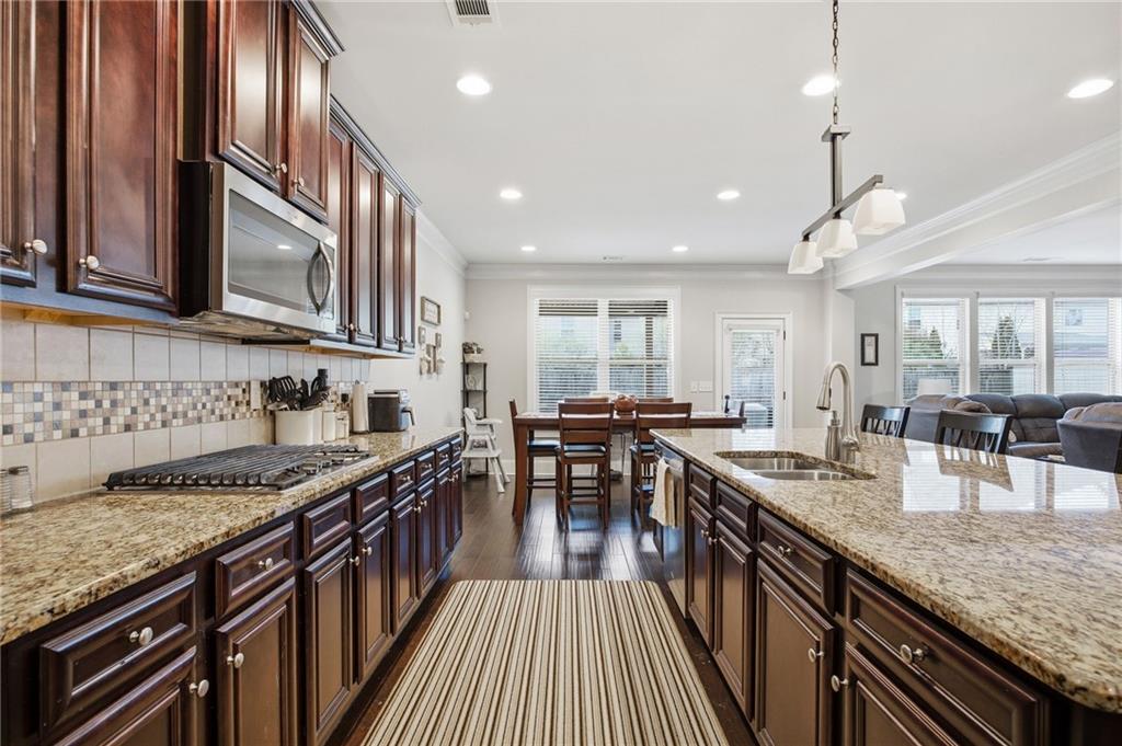 79 Gray Trail Acworth, GA 30101 - Photo 14 of 40 a kitchen with stainless steel appliances granite countertop a stove top oven a sink dishwasher a dining table and chairs with wooden floor