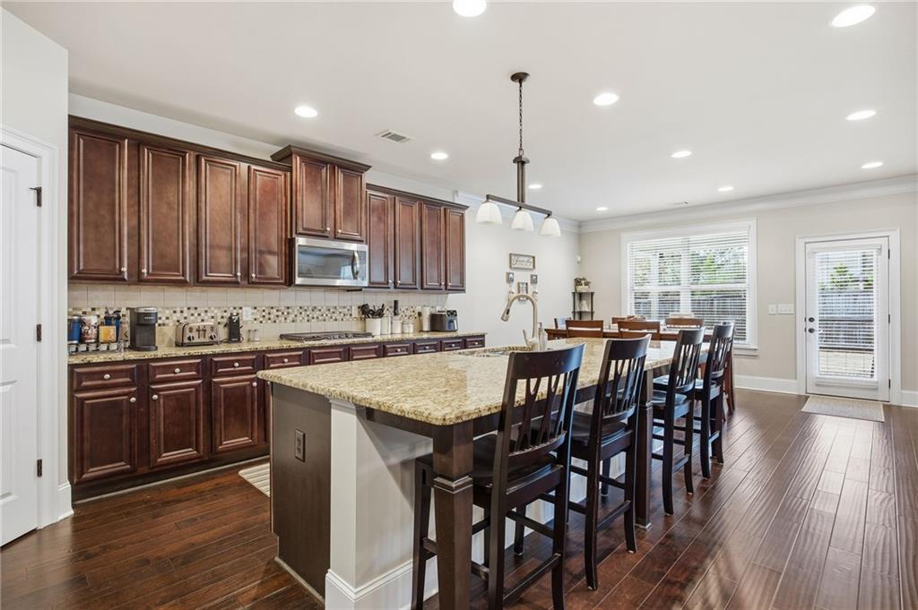 79 Gray Trail Acworth, GA 30101 - Photo 10 of 40 a kitchen with stainless steel appliances granite countertop a stove a sink a microwave a island with a dining table and chairs