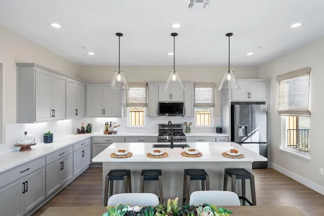 a kitchen with stainless steel appliances kitchen island granite countertop a sink a stove and a wooden floors