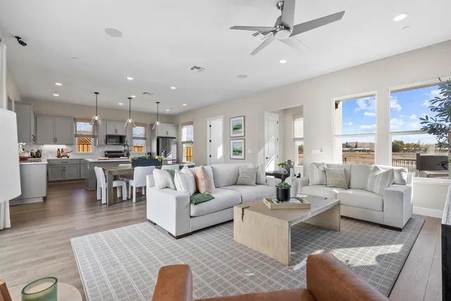 a living room with furniture kitchen view and a wooden floor