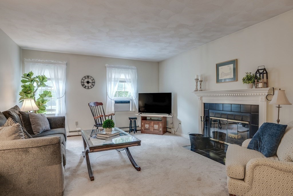 4 Carbone Circle Maynard, MA 01754 - Photo 12 of 38 a living room with furniture a flat screen tv and a fireplace