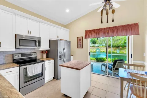 a kitchen with stainless steel appliances kitchen island granite countertop a refrigerator a stove top oven a sink with dishwasher and white cabinets