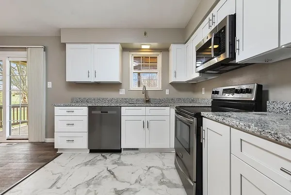 a kitchen with granite countertop cabinets stainless steel appliances a sink and a window