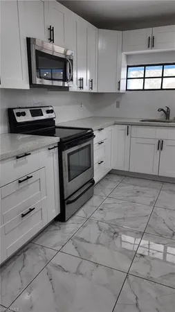 a kitchen with stainless steel appliances granite countertop a stove a sink and a white cabinets