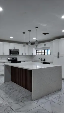 a kitchen with stainless steel appliances a sink a stove a refrigerator cabinets and a kitchen island