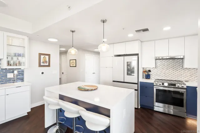 a kitchen with granite countertop a stove a sink a kitchen island with wooden floor and cabinets