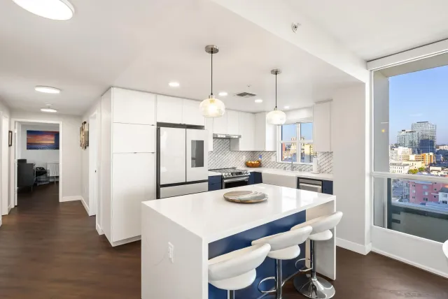 a kitchen with stainless steel appliances kitchen island granite countertop a table chairs and a refrigerator