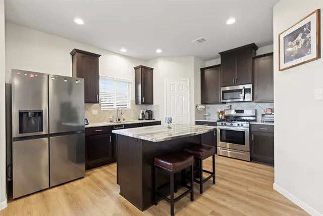a kitchen with stainless steel appliances granite countertop a stove refrigerator sink and microwave